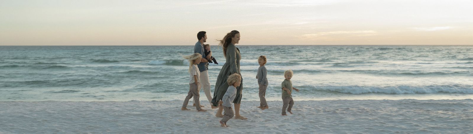 Landon and Kara walking on the beach at sunset with their five boys